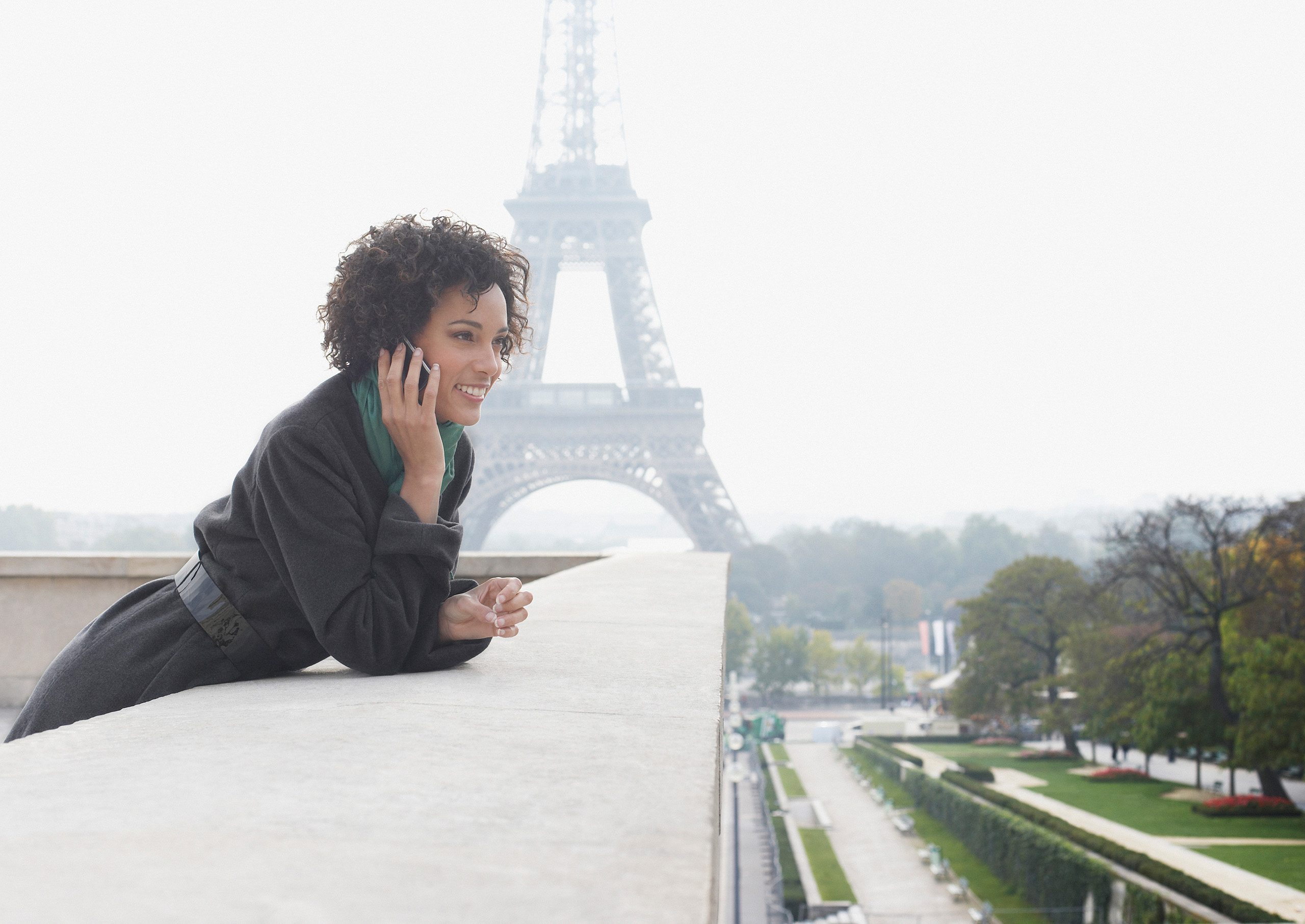 Frau mit Handy vor Eiffelturm